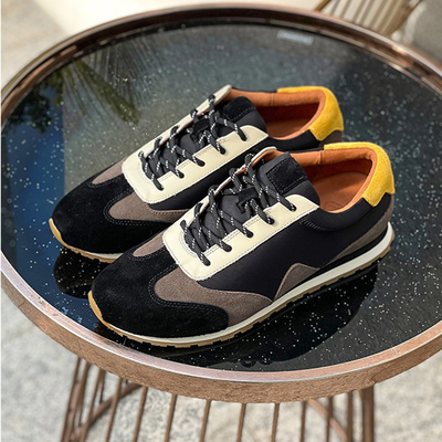 Le scarpe durevoli di sport atletici non slittano il nero di scarpe di cuoio morbido del tennis